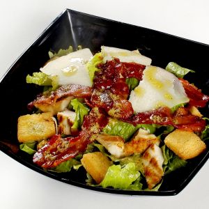 Caesar salad con pollo, pancetta, parmigiano, pane croccante, lattuga